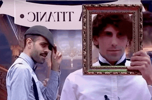 a man is holding a picture frame in front of his face in front of a sign that says " lilivic "