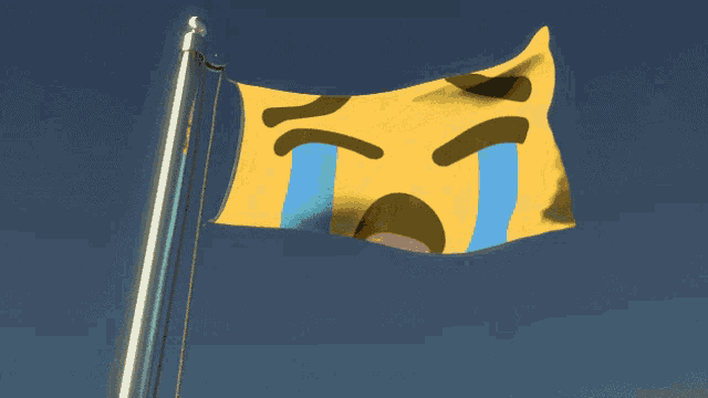 a yellow flag with a crying face on it is flying in the wind