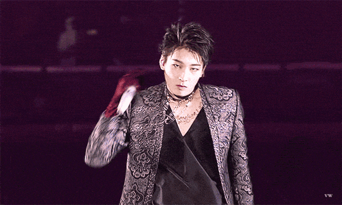 a man wearing a choker and a black jacket is standing on a stage .