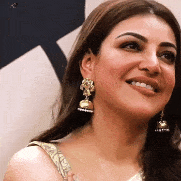 a woman wearing a pair of gold earrings smiles