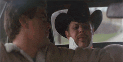 a man in a cowboy hat is sitting in the back seat of a car with another man