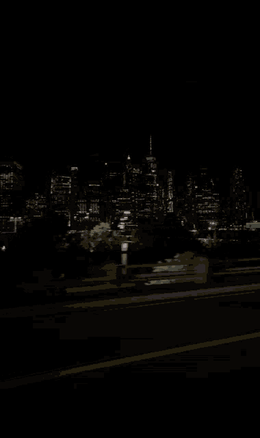 a car is driving down a highway at night in front of a city skyline