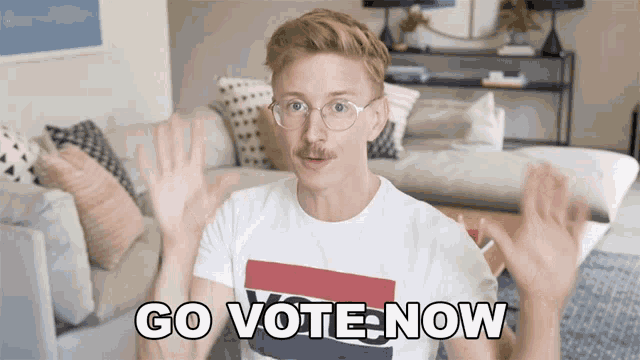 a man in a living room with the words go vote now on the screen