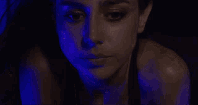 a close up of a woman 's face with a blue light shining on it