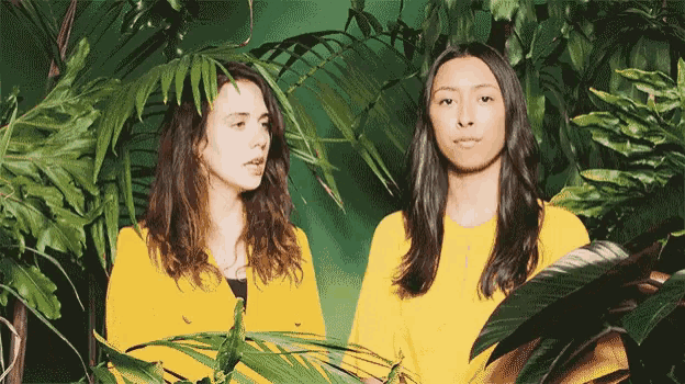 two women in yellow jackets standing next to each other in a jungle