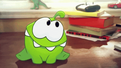 a green cartoon character is sitting on a desk next to a pile of books