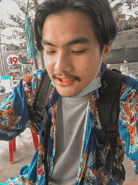 a man wearing a mask and a shirt with tigers on it looks at the camera
