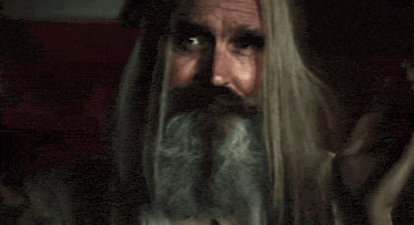 a man with long hair and a beard is making a funny face .