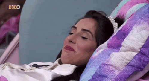 a woman is laying in a hospital bed wearing a tiara and smiling .