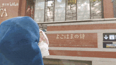 a person wearing a mask stands in front of a building that has chinese writing on it