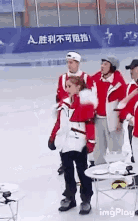 a group of people are standing on a ice rink in front of a sign that says a on it .