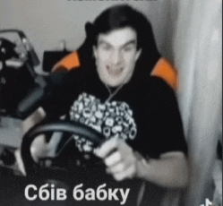 a man in a black shirt is holding a steering wheel and smiling in a video
