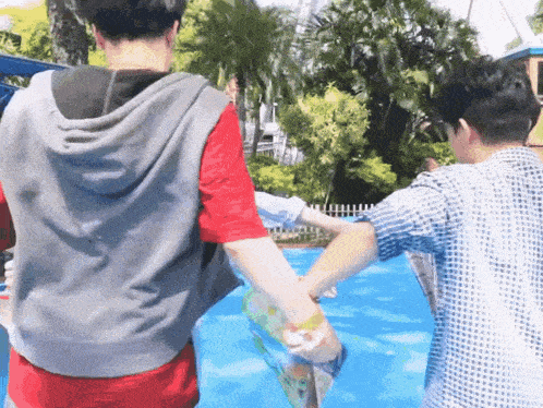 two men are holding hands in front of a swimming pool