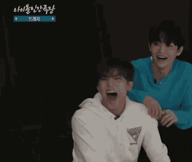 two young men are laughing and one of them is wearing a sweatshirt that says guess