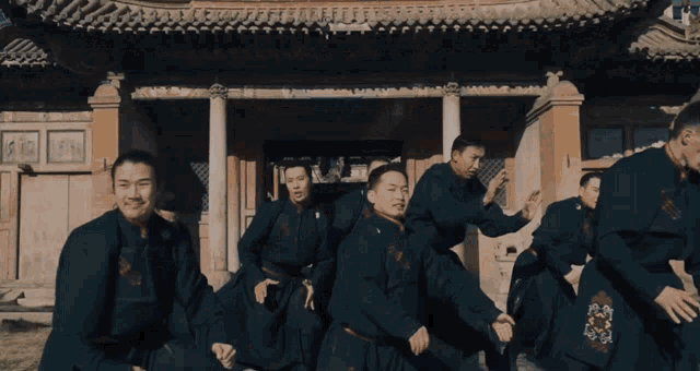 a group of men are standing in front of a building with chinese writing on it