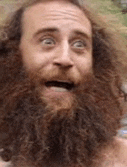a man with a long beard is making a funny face .