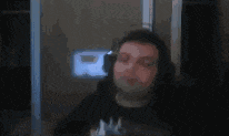 a man wearing headphones and a black shirt is looking at the camera .