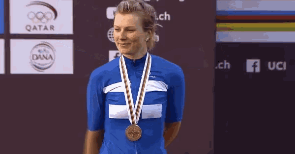 a woman with a medal around her neck stands in front of a dana logo