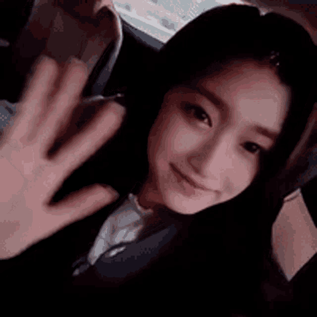 a woman is sitting in the back seat of a car and waving her hand .