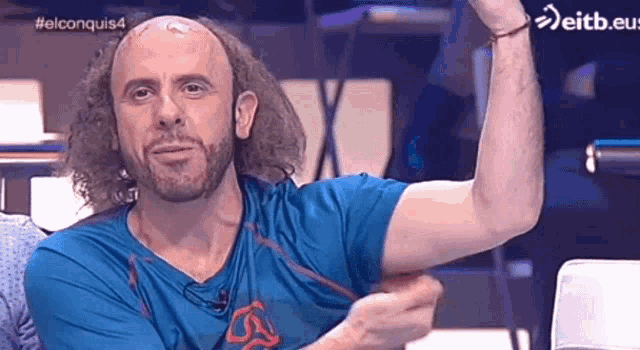 a bald man with curly hair and a beard is flexing his muscles .