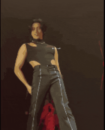 a woman in a black top and gray pants is dancing on stage