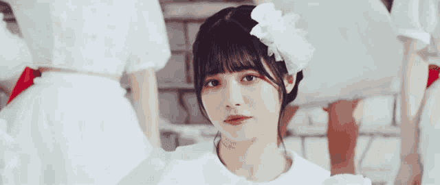 a girl with a flower in her hair is wearing a white dress