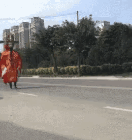 a person in a red robe is walking down a street .