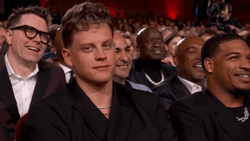 a group of men sitting in a theatre laughing and smiling