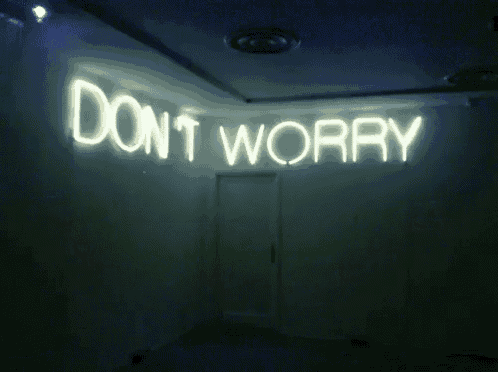 a neon sign that says " do n't worry " is lit up in a dark room