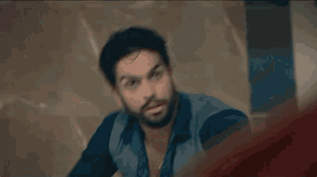 a man with a beard is standing in front of a wall with a bloody hand .