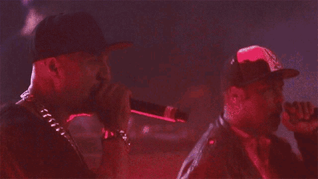 a man singing into a microphone while wearing a baseball cap