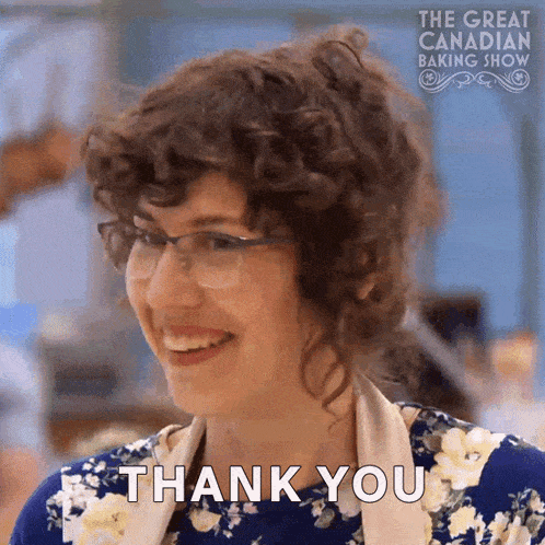 a woman with curly hair and glasses is smiling and says thank you