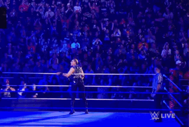 a woman is standing in a wrestling ring with a rope around her waist .
