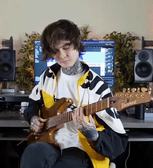 a man playing an ibanez guitar in front of a computer