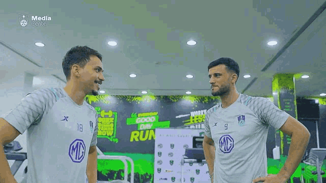 two soccer players are standing next to each other in a gym and laughing