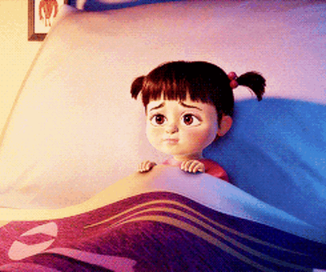 a little girl laying in a bed with a purple blanket