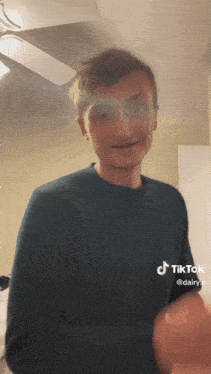 a man wearing a blue sweater has a tiktok sticker on his sweater