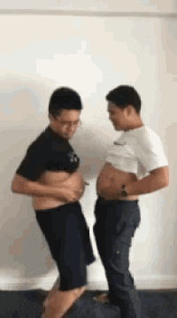 two men are standing next to each other with their shirts off and their stomachs showing .