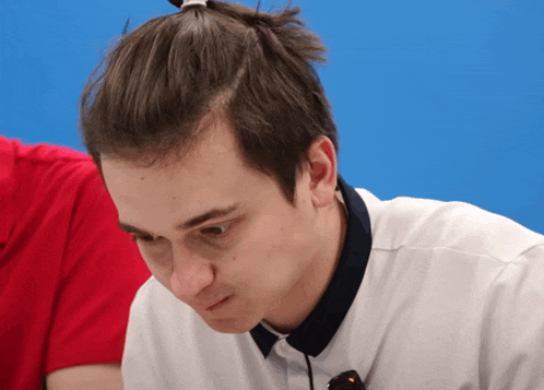 a man with a ponytail on his head looks down at something