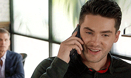 a man is talking on a cell phone and smiling .
