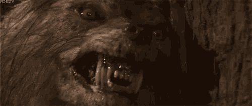 a close up of a werewolf with its mouth open in a cave .