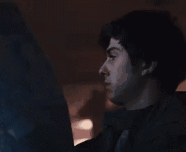 a man is looking at a computer screen in the dark