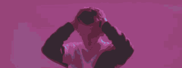 a man is covering his ears with his hands in a purple room .