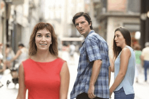 a man in a plaid shirt stands between two women on a city street