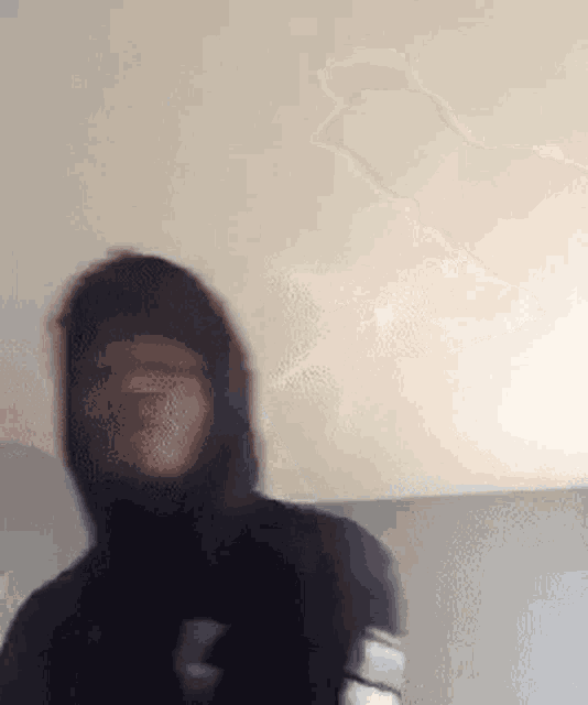 a man in a hoodie is standing in front of a ceiling .