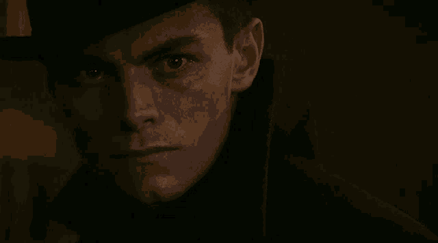 a close up of a man 's face wearing a hat and a coat