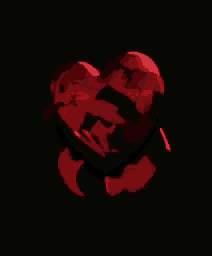 a red heart is floating on a black background in the air .