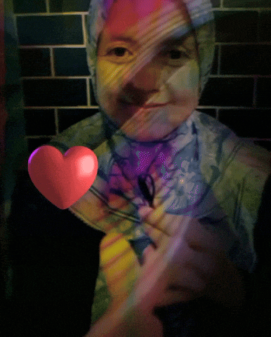 a woman wearing a hijab is holding a pink heart
