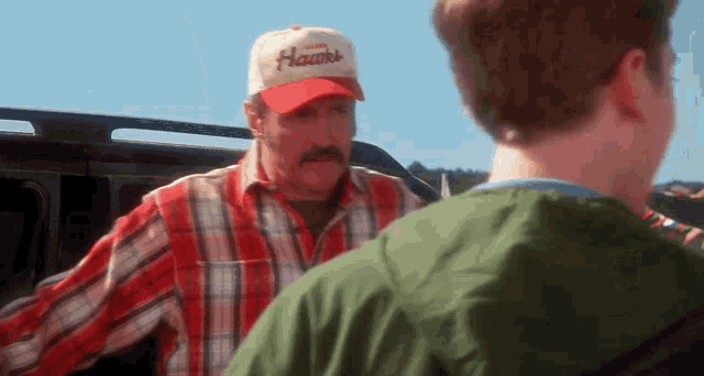a man wearing a hat that says hawks stands next to another man