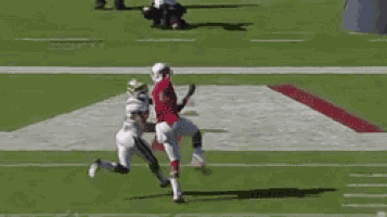 a football player in a red jersey is jumping in the air to catch a ball